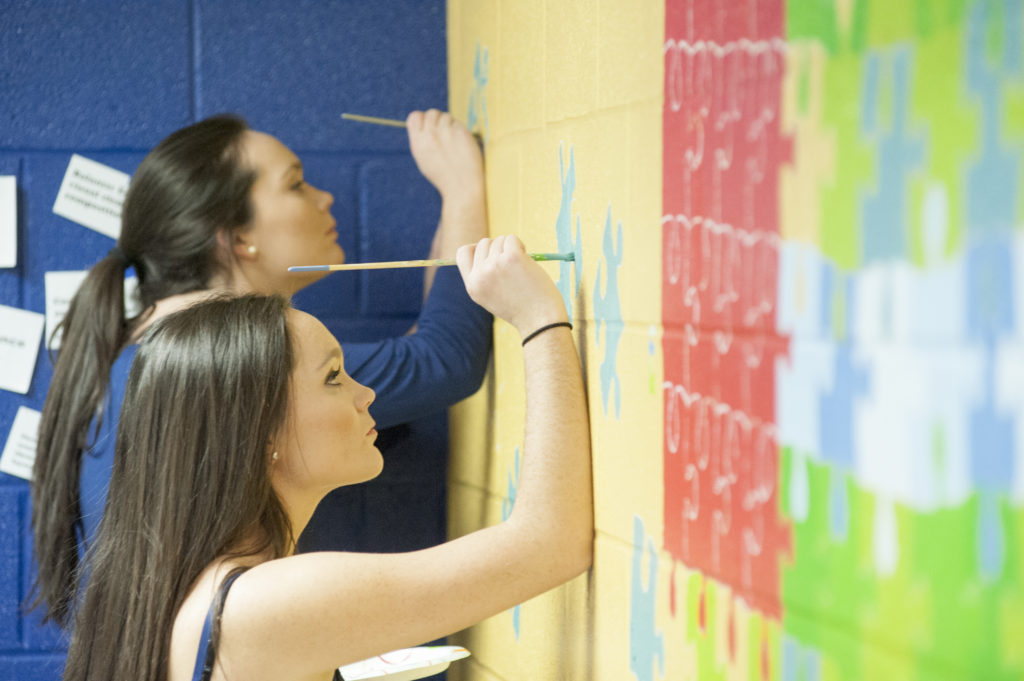 Two students painting a wall.