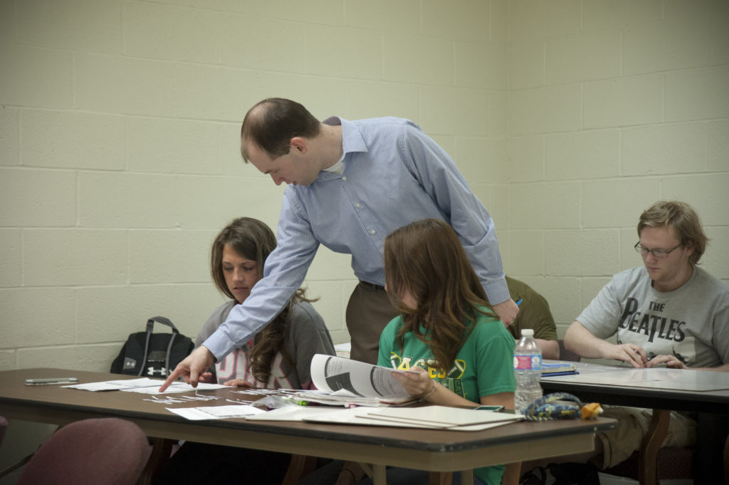 Professor helping students inside of a classroom.