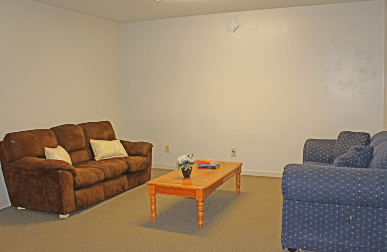 The living room of an apartment in Trustee Hall. There are two couches and a coffee table.