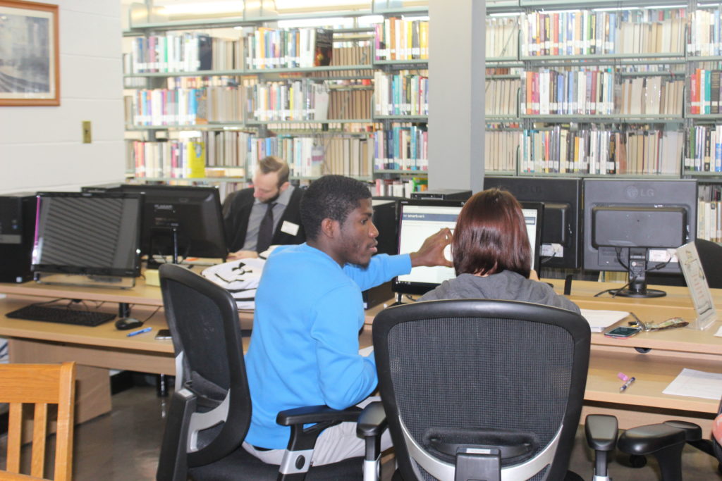 Two students using in a computer in the library computer lab.
