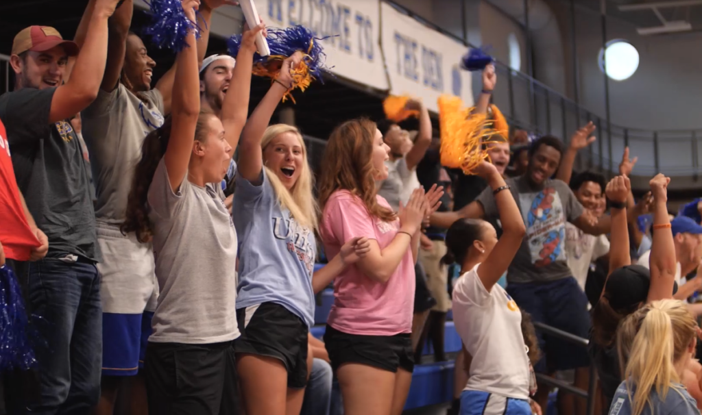 Group of students cheering at a game inside of the gym in the Moore Center.